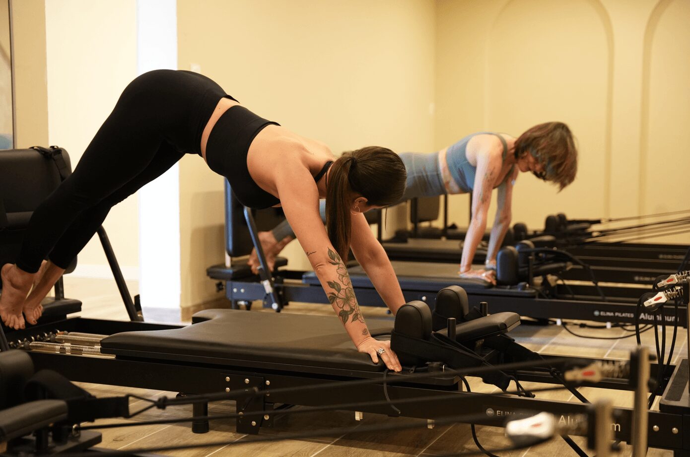Séance de pilates reformer à Montpellier dans un studio lumineux, deux personnes concentrées sur leurs exercices